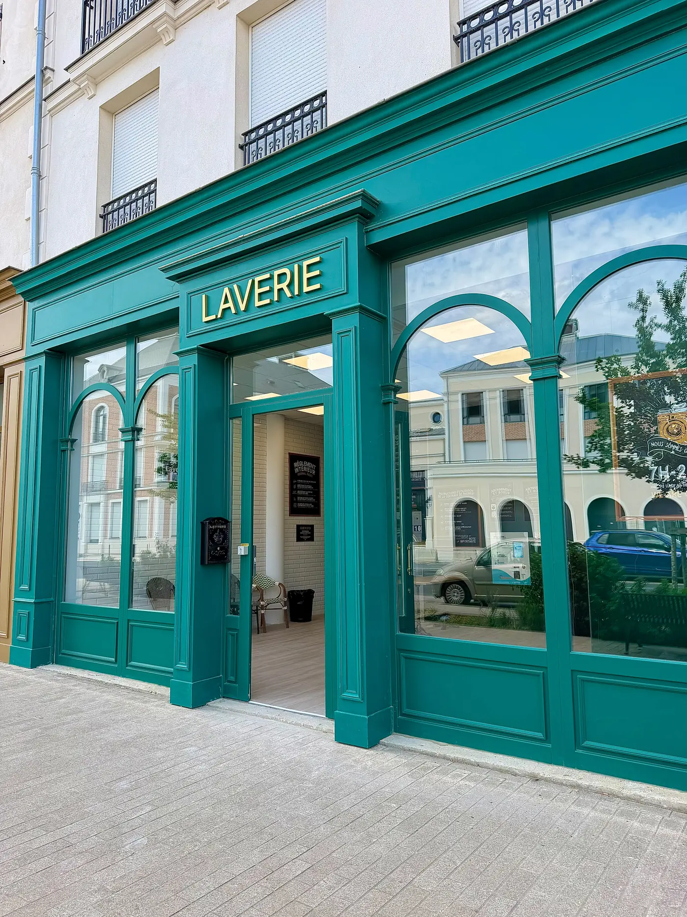 Devanture réelle de la Laverie du Faubourg à Serris, façade verte et lettres dorées