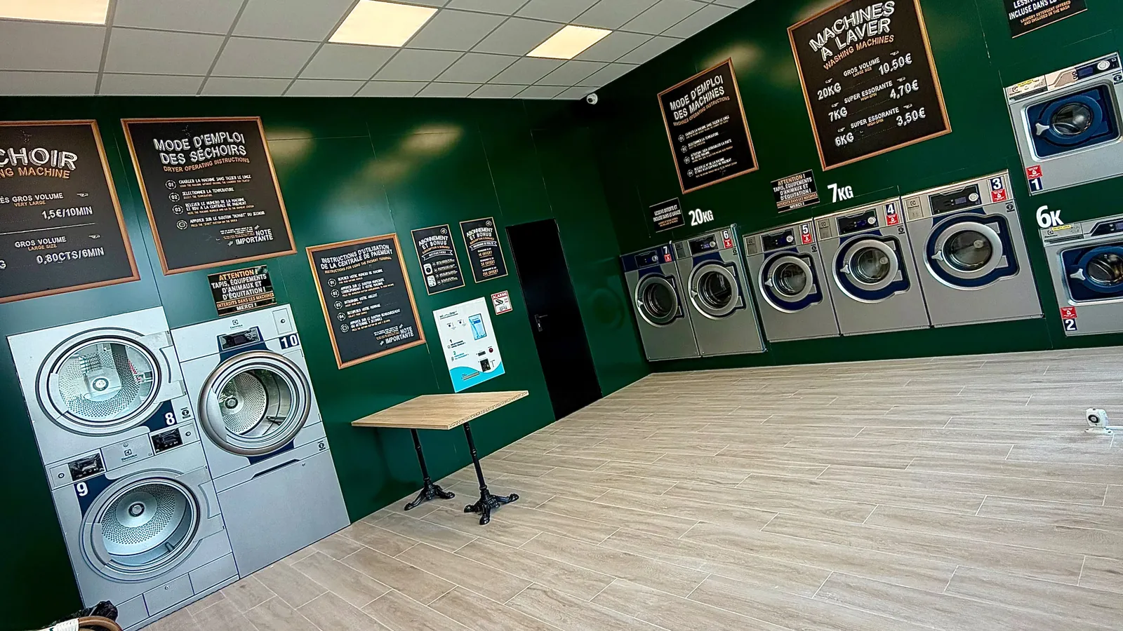 Salle de la laverie : mur vert profond, machines à laver et séchoirs professionnels